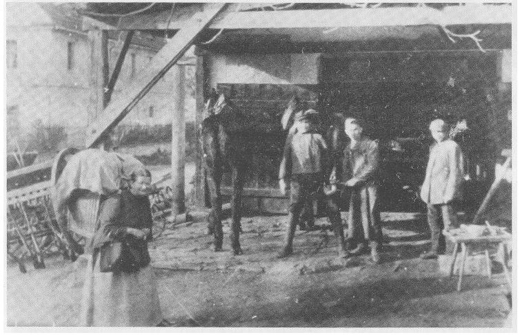 Na zdjęciu Adolf Braunsdorf przed budynkiem kuźni. Na pierwszym planie Hein Reichenbach, sprzedawczyni.JPG